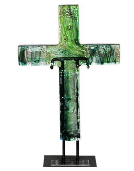 A glass sculpture of a cross with green and clear sections, mounted on a black base stand.