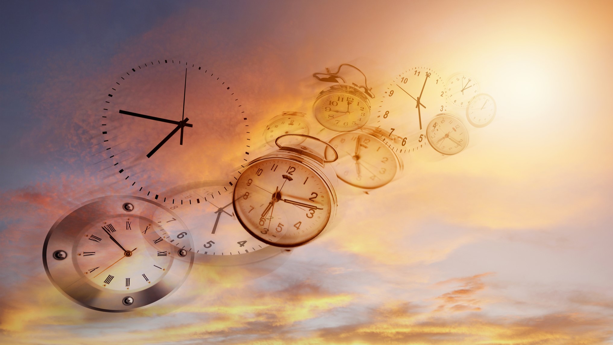 A series of various clocks appear to float and warp in a surreal sky, depicting the concept of the passage of time against a backdrop of a sunset.