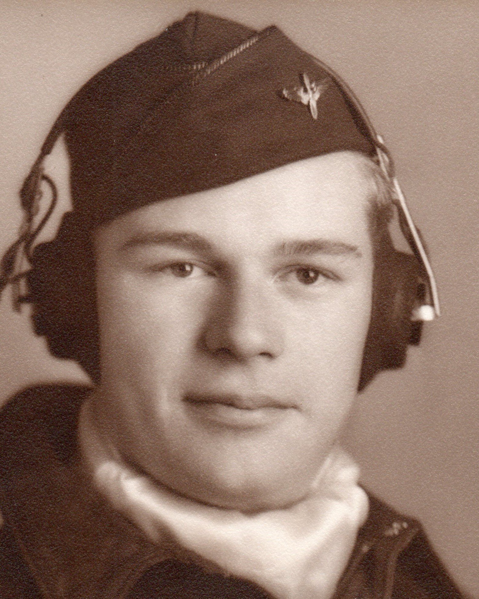 Sepia photograph of a young person in a uniform hat and scarf, facing the camera with a neutral expression.