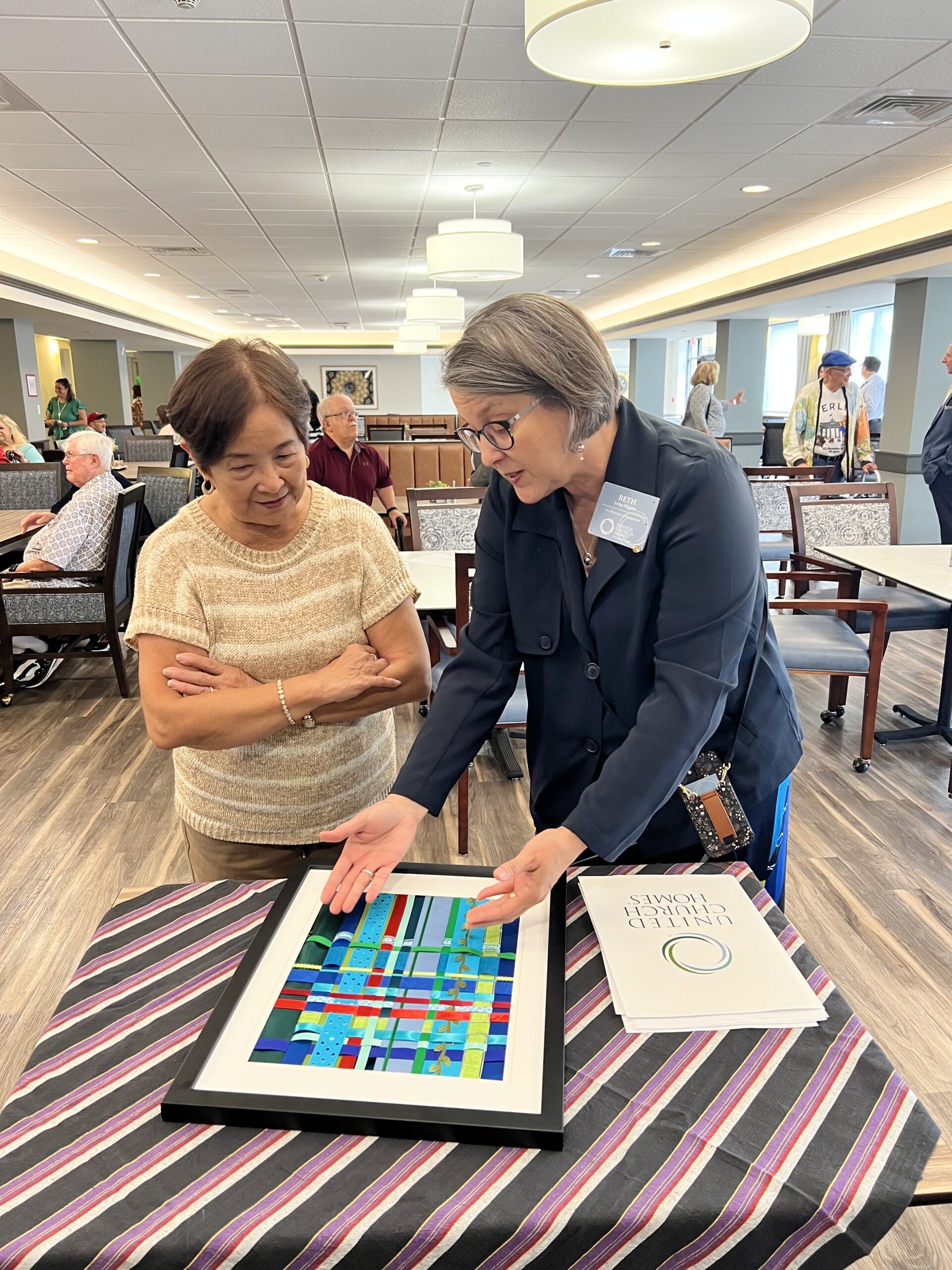 Rev. Beth Long-Higgins showing the weaved ribbons to an event attendee. 