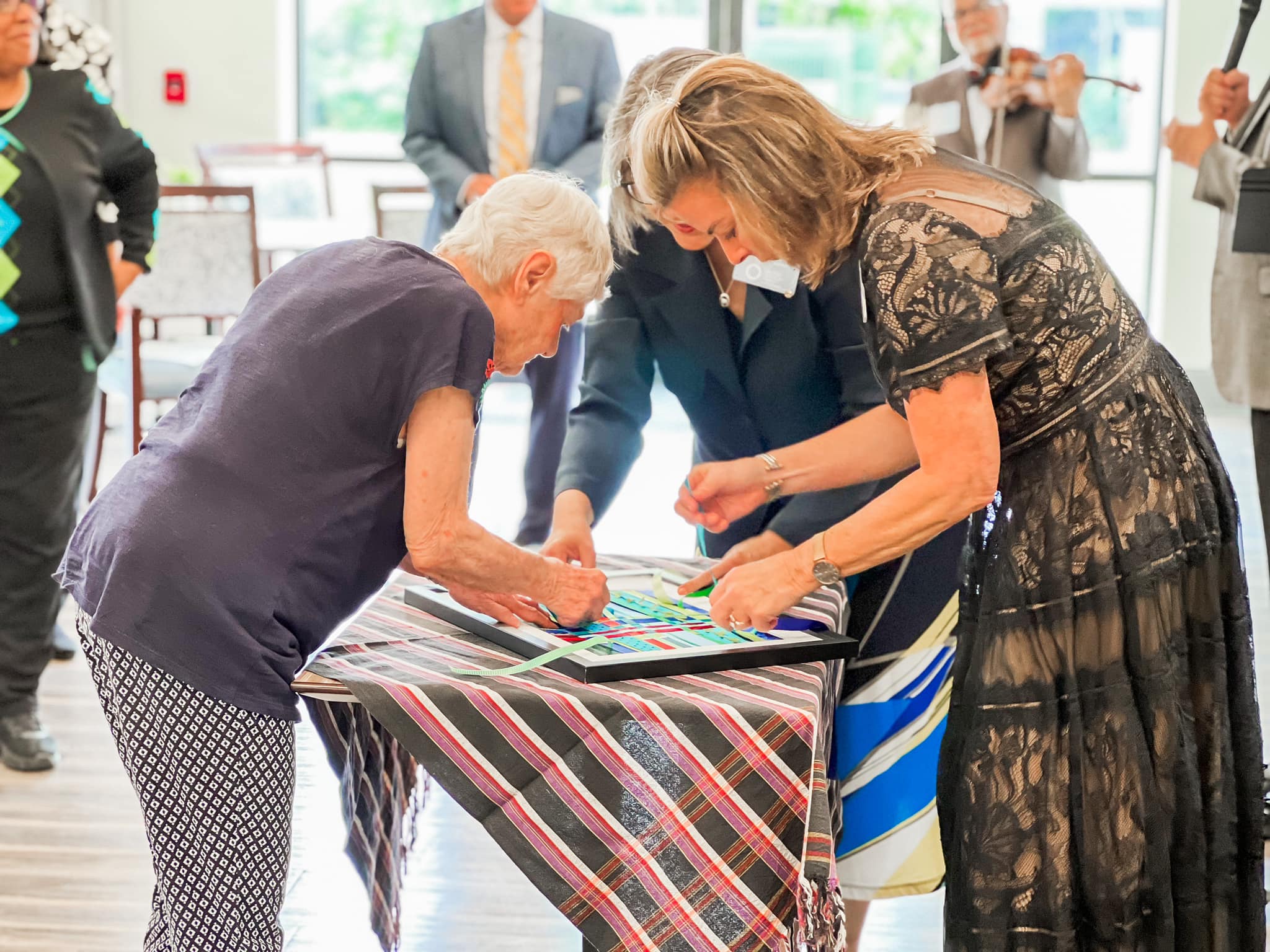 Attendees of the dedication weave ribbons in a frame.