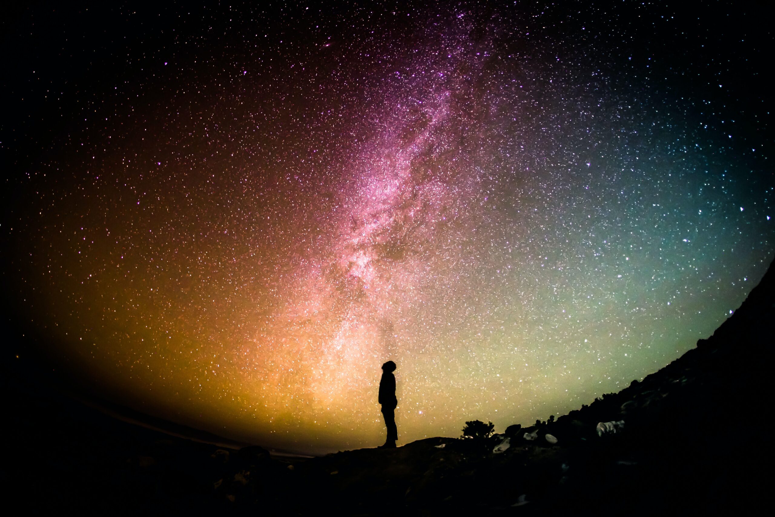 A silhouetted person stands under a star-filled sky with the Milky Way visible.